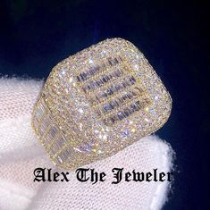 a large diamond ring sitting on top of a white sweater with the words alex the jeweler above it