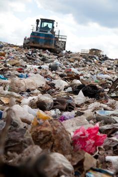 a large pile of garbage with a bulldozer in the background