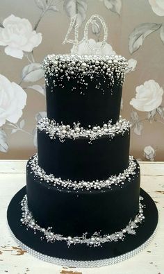 a three tiered black wedding cake with white flowers