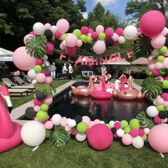 an outdoor pool decorated with pink, green and white balloons for a flamingo themed birthday party