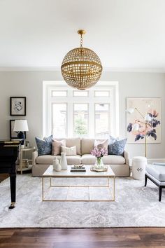 a living room filled with furniture and a chandelier hanging over the couches