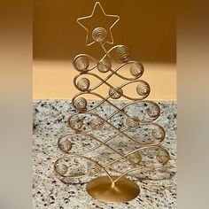 a metal christmas tree on a marble countertop with a gold star and swirls