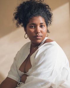 a woman sitting on the floor with her arms crossed and looking off to the side