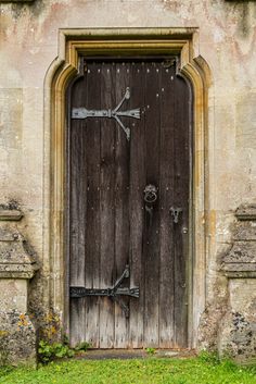 an old wooden door with two crosses on the front and side, surrounded by grass