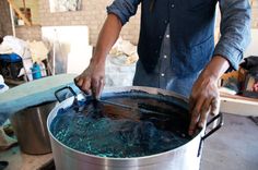 a man is standing in front of a large pot filled with water and holding the lid