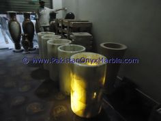 there are many vases lined up on the table and one man is standing next to them