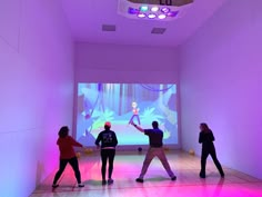 three people are standing in front of a projection screen while one person is holding a wii controller