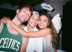 three young people are hugging each other in front of a basketball player wearing a green and white uniform