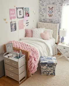 a white bed topped with pillows and blankets next to a wall covered in pictures on the walls