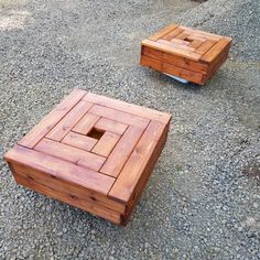 two square wooden tables sitting on top of a gravel covered ground next to each other