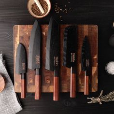 five knives are on a cutting board next to some spices