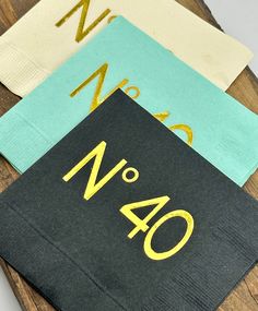 four napkins with gold numbers on them sitting on a wooden table next to each other