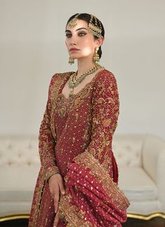 a woman in a red bridal gown with gold jewelry on her head and shoulders