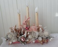 a pink and white centerpiece with candles in the middle on top of a table