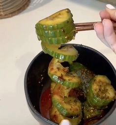 someone is holding chopsticks over some food in a bowl on the counter top