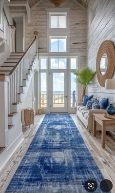 a large blue rug in the middle of a living room with stairs leading up to an open floor plan