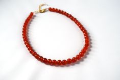 "Carnelian is a lovely semi-translucent stone in a rich orangey red color. It is highly polished for a beautiful shining quality. The stones themselves are a larger size- about 8mm around- so this is a necklace that will make a nice statement. The necklace is 15\" long with a 2\" extender chain, or it can be finished with two rings in the 18th Century style. This allows you to run a ribbon of your choice through the rings and tie it tightly on the neck, like a choker, or loose so it hangs down l Red Carnelian Hand-strung Beaded Necklaces, Red Carnelian Beaded Necklace Hand-strung, Hand-strung Red Carnelian Beaded Necklaces, Red Polished Carnelian Beads, Polished Red Carnelian Beads, Red Carnelian Beads For Gift, Red Carnelian Beads For Gifts, Red Beaded Necklaces, Carnelian Necklace