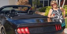 a woman standing next to a black sports car