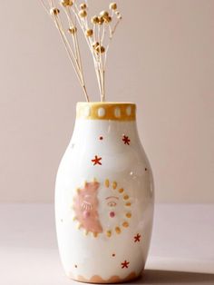 a white vase with flowers in it sitting on a table next to a pink wall