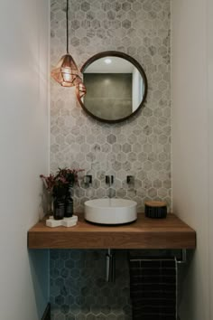 a bathroom sink sitting under a mirror on top of a wooden counter next to a plant