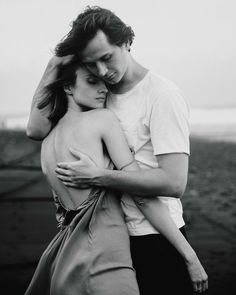 black and white photograph of a man hugging a woman's head in front of a field