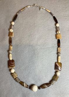 I wanted  to create a necklace that was comprised of browns, tans and beige tones. The sterling silver beads are Karen hill tribe  creations. In this necklace I've used fossil coral,bone, banded agate and a varied group of jaspers. There is also a pair of very old carved beads from Afghanistan. Hand-strung Brown Agate Jewelry, Brown Agate Hand-strung Jewelry, Unique Brown Jewelry With Natural Variations, Rustic Brown Hand-strung Necklaces, Brown Agate Hand-strung Necklaces, Unique Brown Agate Beaded Necklaces, Rustic Brown Gemstone Bead Necklaces, Earthy Hand-strung Brown Jewelry, Artisan Brown Agate Necklace