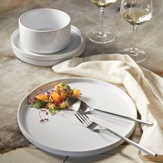 a white plate topped with food next to two wine glasses