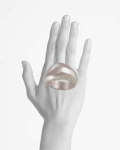 a woman's hand with a gold ring on top of her left hand, against a white background