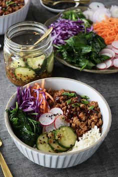 a bowl filled with meat and vegetables next to two bowls of salads on top of a table