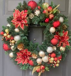 a christmas wreath with poinsettis and other ornaments hanging on the front door