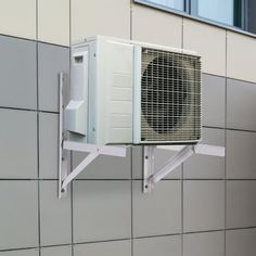 an air conditioner mounted to the side of a wall next to a gray tiled wall