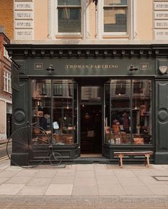 an old fashioned bicycle is parked in front of a storefront on a city street