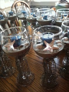 several wine glasses filled with sand and starfish