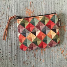 a multicolored zipper pouch sitting on top of a wooden table next to a wall