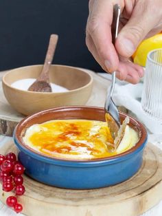 a person is spooning into a bowl of soup with cranberries on the side