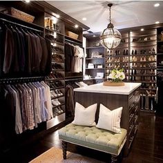 a walk - in closet with lots of clothes on shelves and a bench next to it