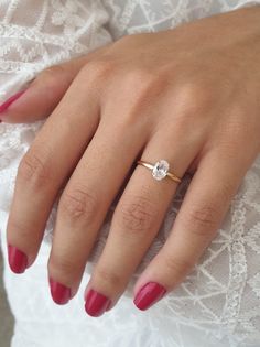 a woman's hand with red nails and a ring on her finger, wearing a white lace dress