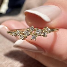 a woman's hand holding a gold ring with five small diamonds on the side