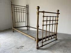 an old metal bed frame sitting in a room with concrete flooring and white walls