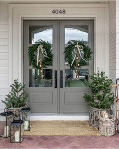 two christmas wreaths on the front door of a house