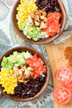 two wooden bowls filled with black beans, tomatoes and chicken next to a cutting board