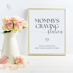 a white vase filled with pink flowers next to a framed sign that says, mommy's craving station