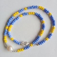 This minimalist handmade dainty necklace is made of yellow and blue opaque beads, silver glass seed beads with natural freshwater pearl bead. Stylish beaded necklace  is a perfect addition to summer beach outfits and it's a beautiful handmade gift for women and girls. Similar chokers are available in different color combinations. The length of the necklace is 40,5 cm.  All necklace metal findings are nickel-free and silver plated. At the request the length of necklace can be changed.  Please, pay attention to FAQs and if you have any question, don't hesitate to ask.  Thank you for visiting my shop! Minimalist Blue Beads For Gift, Dainty Blue Necklaces For Summer, Blue Dainty Necklace With Colorful Beads, Dainty Blue Necklace With Colorful Beads, Minimalist Blue Beaded Chain Necklaces, Minimalist Handmade Blue Beaded Necklaces, Minimalist Blue Beaded Chain Necklace, Blue Single Strand Minimalist Beaded Necklaces, Blue Minimalist Necklaces With Spacer Beads