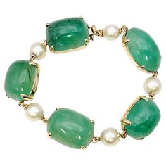 We are thrilled to feature this absolutely stunning bracelet with a bold and beautiful design. Five incredible natural cabochon emerald stones line the wrist, filling it with color. Each stone is unique in its shade of green and natural variations, making this a truly one of a kind piece. In between each emerald is a single round white Akoya pearl with a subtle pink overtone, adding a bit of contrast to the sizeable colored stones. The gemstones are set in polished 14 karat yellow gold, enhancin Elegant Green Gemstone Cabochons, Elegant Green Cabochon Bracelets, Elegant Green Bracelets With Gemstone Accents, Green Cabochon Bracelet For Formal Occasions, Green Cabochon Bracelets For Formal Occasions, Formal Green Cabochon Bracelets, Formal Green Cabochon Bracelet, Elegant Natural Emerald Gemstones, Elegant Natural Emerald Stones