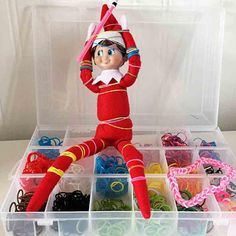 an elf is sitting in a plastic container filled with beads and other crafting supplies