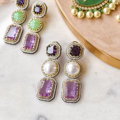 Look ravishing and take your love for long dangle earrings to another level! Gorgeous pair of earrings luxuriously studded with amethyst, pearl and CZ stones - perfect to wear them in your favorite fancy events to make all eyes rest on you. Approximate earrings length is 3.2". Designed over high-quality brass as base metal with silver and gold plating. Made by order. Kindly allow 4-6 weeks for the delivery of this item. For custom or urgent requests, please contact support@alacouture.com. *Please Note: We use faux stones and beads in all of our jewelry Unique Gift Cards, Long Dangle Earrings, Faux Stone, All Eyes, Green Stone, All About Eyes, Cz Stone, Base Metal, Free Giveaway