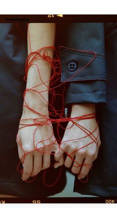 a woman's hands with red string attached to them