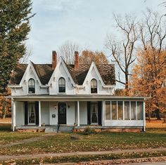 a white two story house sitting on the side of a road in front of trees