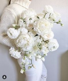 a woman holding a white vase filled with flowers