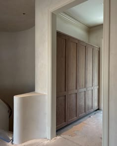 an empty room with wooden closets and stairs in the middle, surrounded by white walls